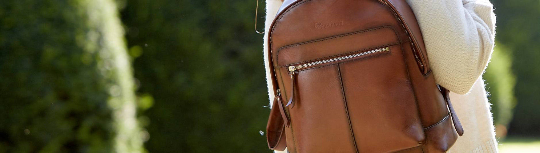 Close up of Brown Leather backpack over a cream jumper